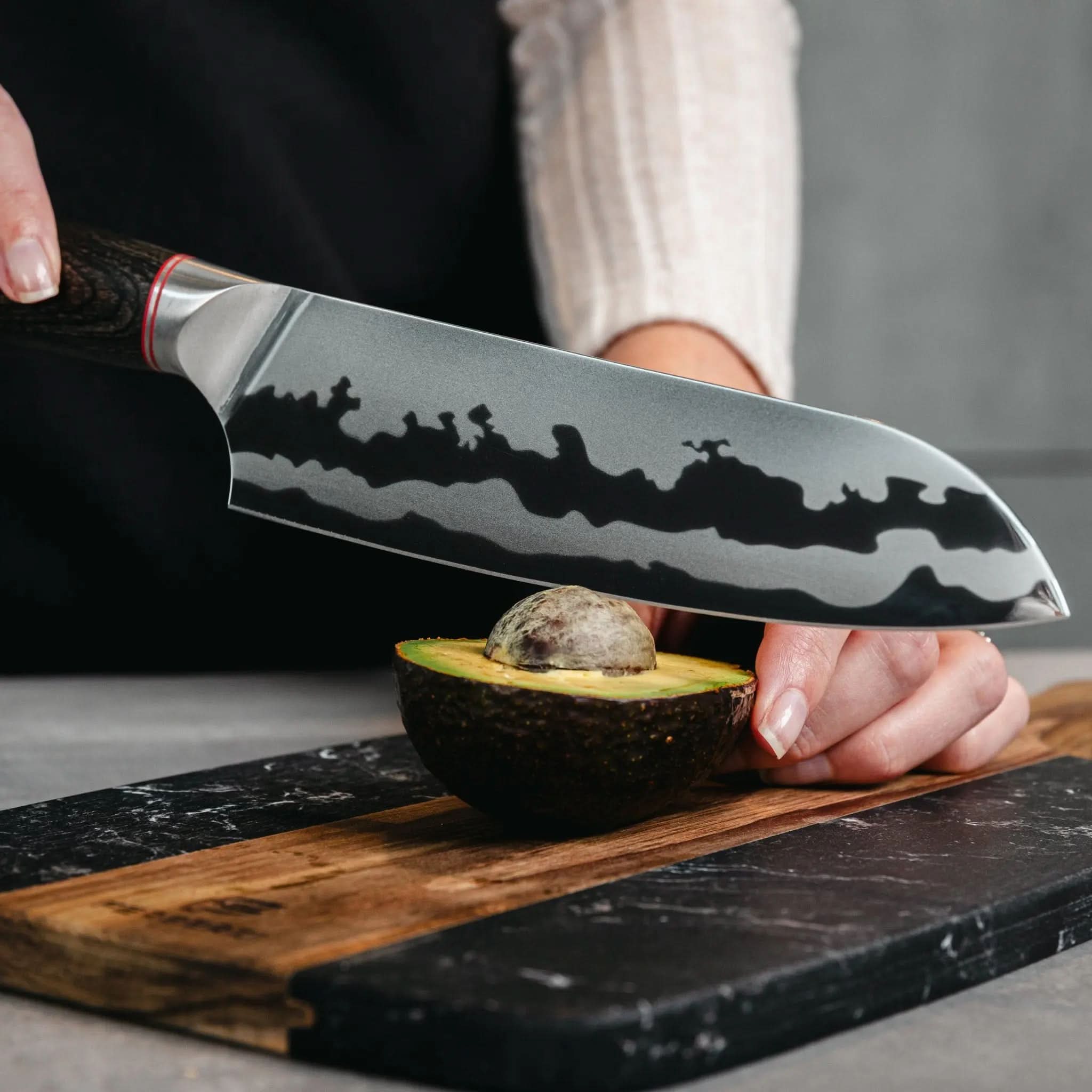 Santoku mes met houten handgreep snijdt avocado op zwarte marmerlook snijplank