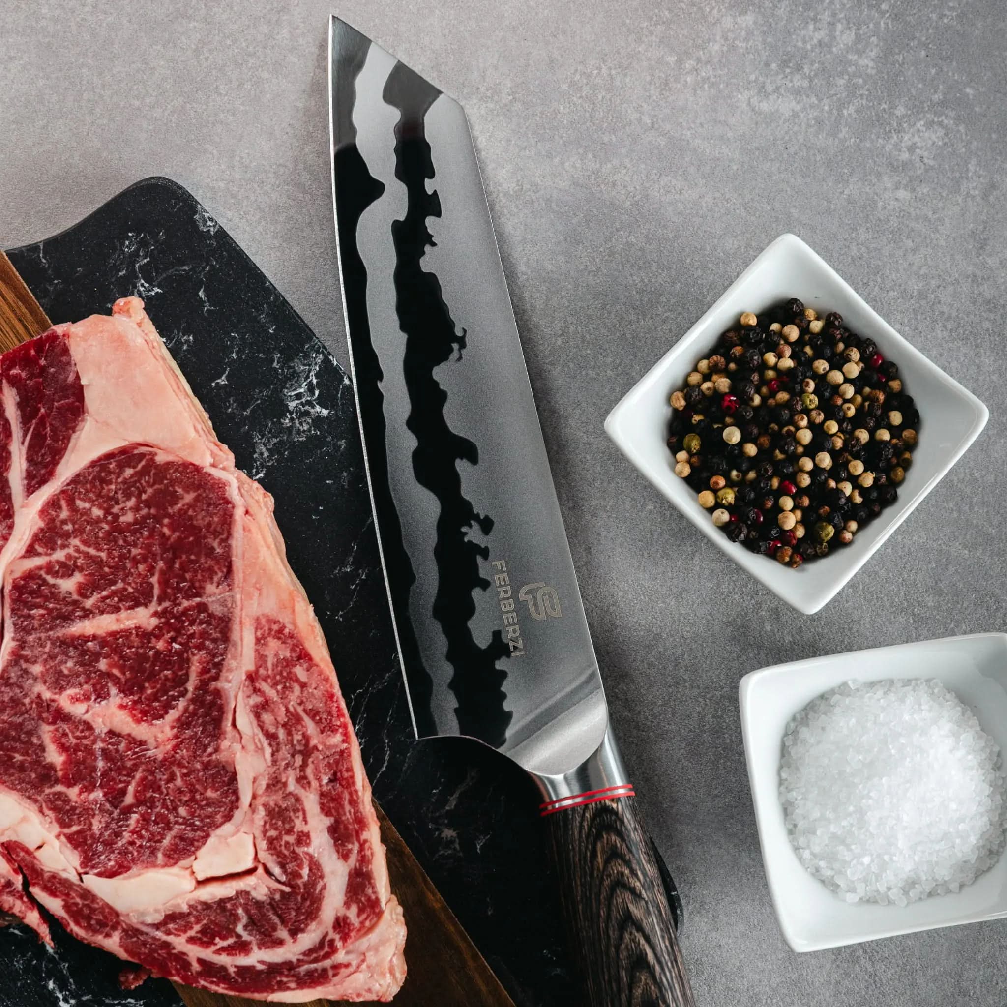 Kiritsuke mes met houten handgreep en spiegelend golfpatroon naast steak op zwarte marmerlook snijplank