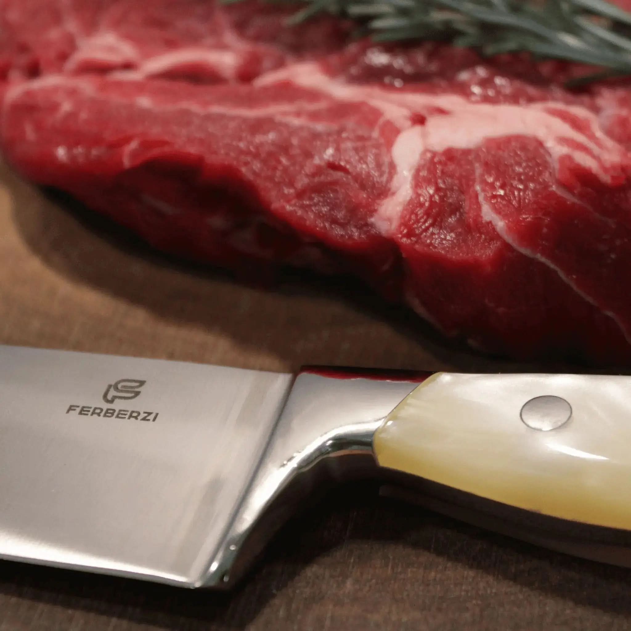 Detail van koksmes met parelwit acryl handvat naast steak op acaciahouten snijplank