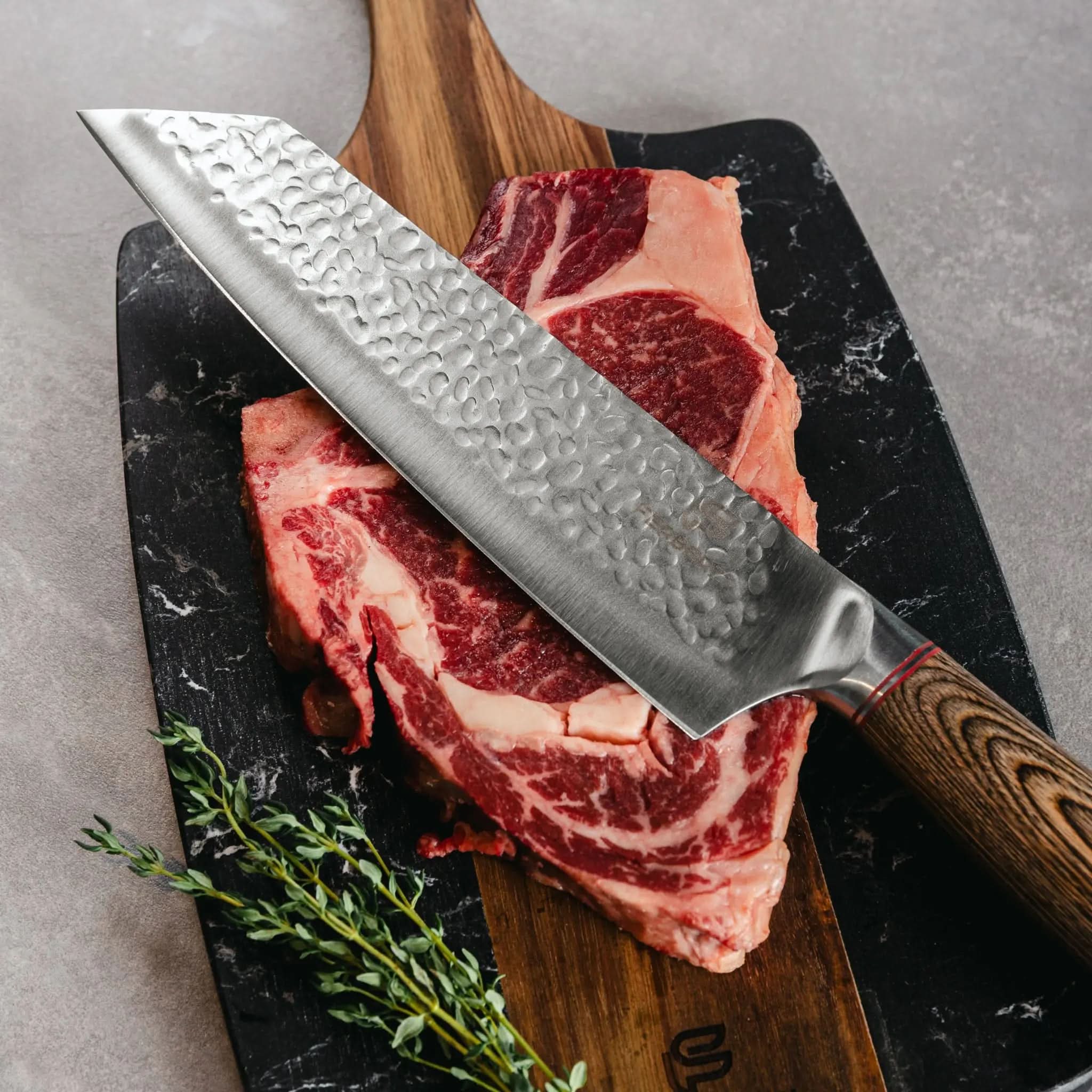 Gehamerd koksmes met houten greep op steak en zwarte marmerlook snijplank