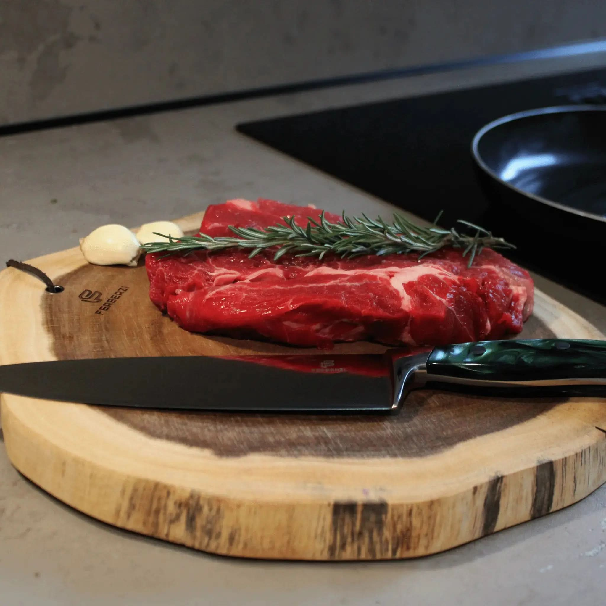Koksmes met smaragdgroen acryl handvat op acaciahouten snijplank met steak en rozemarijn