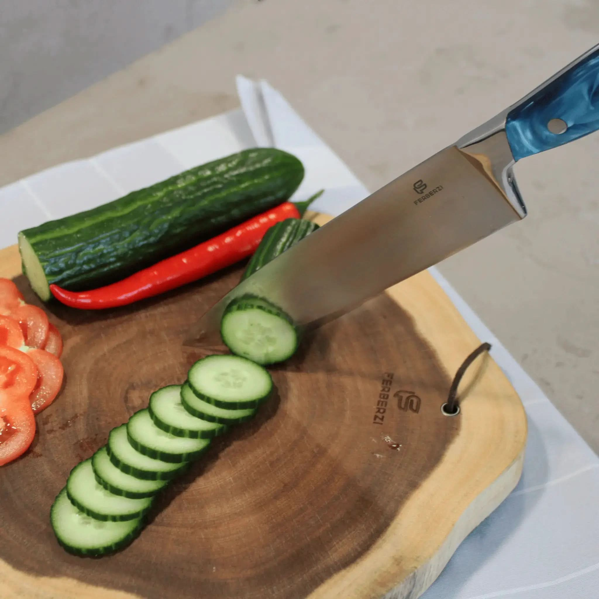 Koksmes met blauw acryl handvat snijdt komkommer op acaciahouten snijplank