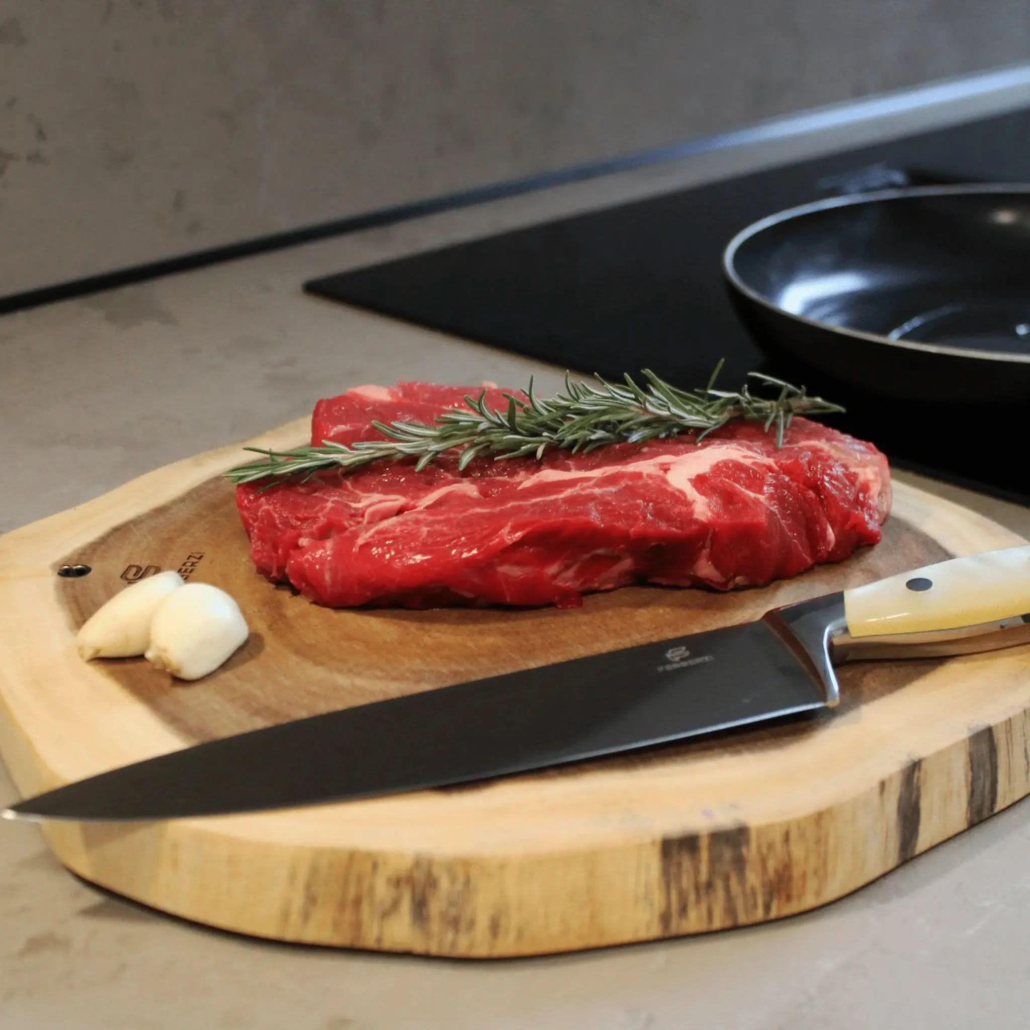 Koksmes met parelwit acryl handvat op acaciahouten snijplank met steak en rozemarijn